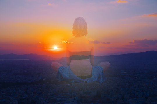 Double multiply exposure portrait of a young woman sits in a pose of lotus meditating outdoors back view, combined photograph of nature light, sunrise or sunset sky. Yoga inner mind power hope concept