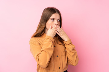 Ukrainian teenager girl over isolated pink background covering mouth and looking to the side