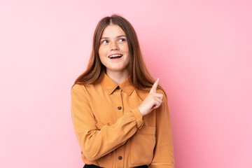 Ukrainian teenager girl over isolated pink background surprised and pointing side