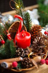 Red candle with the twigs of the spruce and cones
