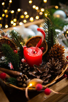 Red candle with fir branches and cones. Bokeh in the background