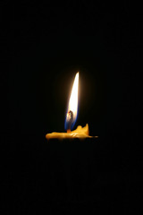 One or Single yellow light candle burning brightly in the black background, candle light isolated black in dark night.