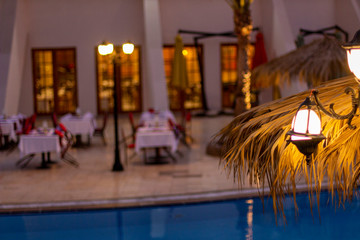 The restaurant by the pool is ready for dinner with white tablecloths and red velvet chairs.