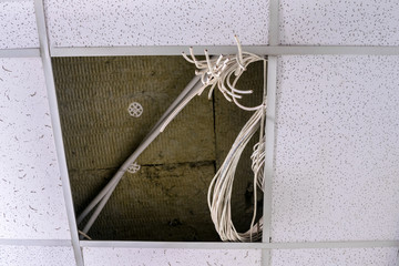 There are dangling white cables above the false ceiling. Electrical wiring is laid over a false...