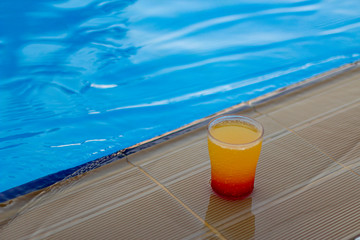 Colorful cocktail on the edge of a bright blue pool.