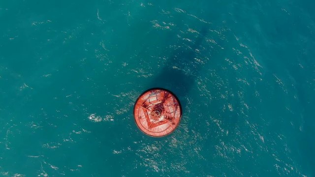 Aerial shot of a red buoy in a beautiful blue sea