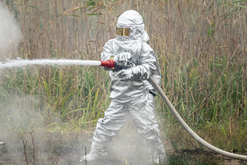 Firefighter in protective suit works with water hose. Fighting for a fire attack