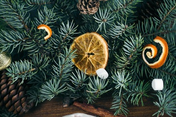 a slice of orange lies in the fir branches, dressed up with Christmas toys, cones, marshmallows