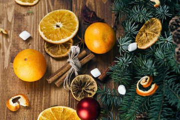 Fototapeta na wymiar pine branches with cones, cinnamon, orange slices, tangerines, marshmallows and toys are on the wood. Christmas background