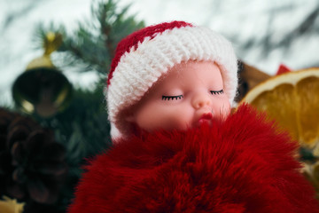 Portrait of a little child toy in Santa Claus costume. background of christmas tree and christmas toys.