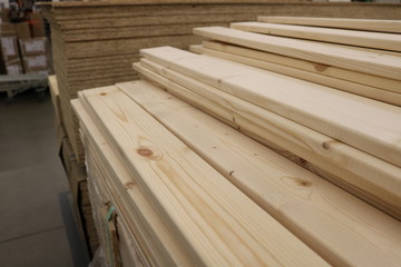 Folded planed boards on the background of other goods wholesale warehouse. Shot under shop lighting