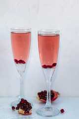 Holiday pomegranate drink. Pink wine. In the background are pomegranate slices. White background. Champagne. New Year. Christmas. Foreground. 
