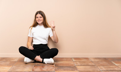 Fototapeta na wymiar Ukrainian teenager girl sitting on the floor happy and counting three with fingers