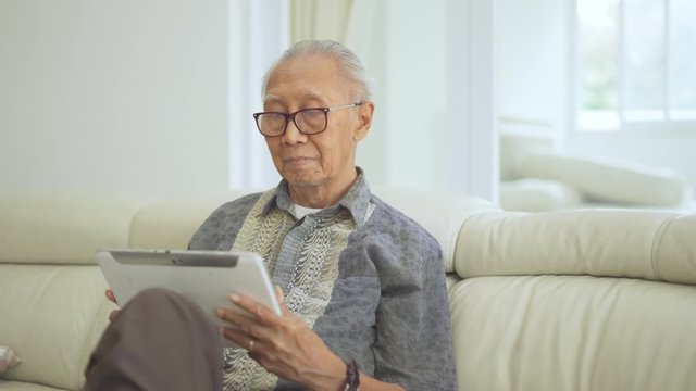 Aged man using a digital tablet on the couch