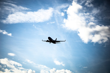 Silhouette of a plane's arrival, on a descent, with a vibrant blue sky.