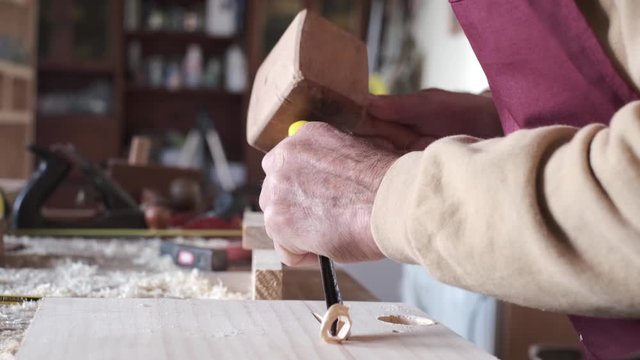carpenter working with a wooden hammer and a gouge