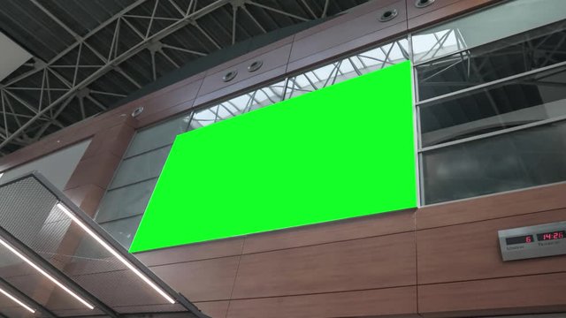 Empty blank widescreen billboard with green screen, alpha channel. Chroma key frame on airport hall, big banner for marketing. 