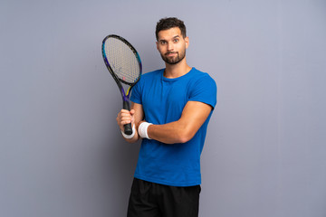 Handsome young tennis player man making doubts gesture while lifting the shoulders