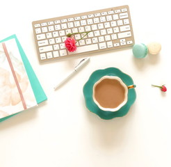 Flat lay women's office desk. Female workspace with laptop, flowers roses,  accessories, notebooks, cup of coffee on white background. Top view feminine background.