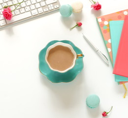 Flat lay women's office desk. Female workspace with laptop, flowers roses,  accessories, notebooks, cup of coffee on white background. Top view feminine background.