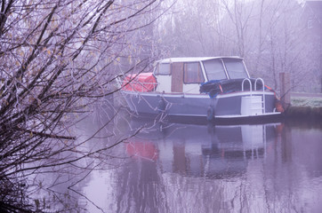 old boat in the river on a foggy morning in the Netherlands. Frozen mist on plants. ashore.