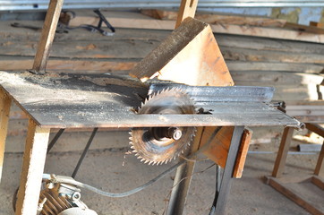 An old electrical device for sawing wooden boards stands in an old dusty workshop. In the background are composed of the old Board