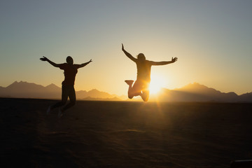 Fototapeta premium silhouette of young people jumping sunset