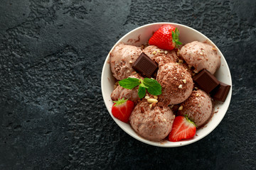Chocolate Ice Cream with dark chocolate bars, strawberry and hazelnuts in a white bowl