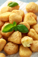 Fried mozzarella, cheddar cheese bites, balls with ketchup on white wooden board