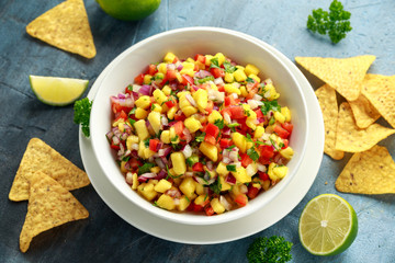Bowl of fresh Mango Salsa with nachos chips and herbs. Healthy Vegan, Vegetables food.