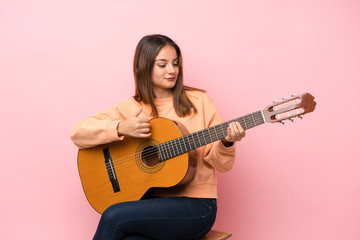 Fototapeta premium Young brunette girl with guitar over isolated pink background
