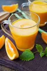 Two glass mugs of freshly squeezed orange juice stand on a wooden background. Horizontal orientation.