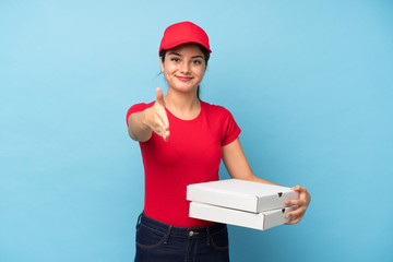 Young woman holding a pizza over isolated pink wall handshaking after good deal