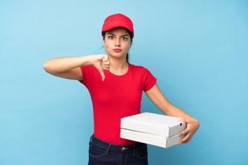 Young woman holding a pizza over isolated pink wall showing thumb down sign