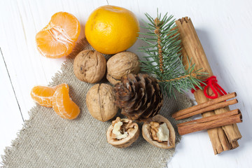 Название: Tangerines, walnuts, cinnamon sticks and spruce branch. Lying on a piece of linen. Against the background of white painted boards.