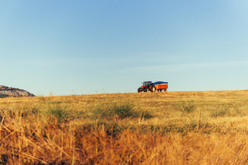 Fototapeta premium Red agricultural tractor with truck stands on planting field.