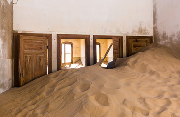 Abandoned and forgotten building and room left by people and being taken over by encroaching sandstorm, Kolmanskop ghost town, Namib Desert