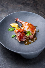 Traditional roasted Christmas duck breast and leg with orange slice and herbs as closeup on a modern design plate