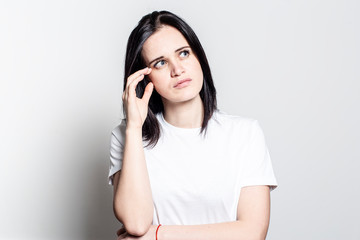 Pensive, beautiful young woman looks away and tries to remember something.