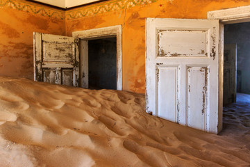 Fototapeta na wymiar Abandoned and forgotten building and room left by people and being taken over by encroaching sandstorm, Kolmanskop ghost town, Namib Desert