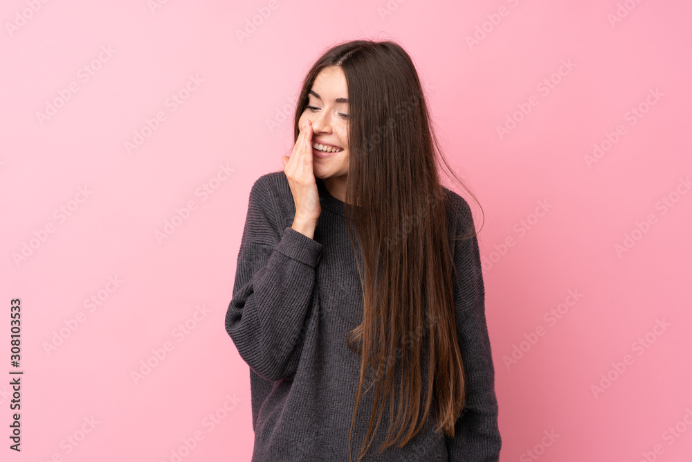 Wall mural Young woman over isolated pink background smiling a lot