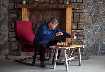 One man sits on chair in country house and plays chess with himself. Waiting and loneliness....