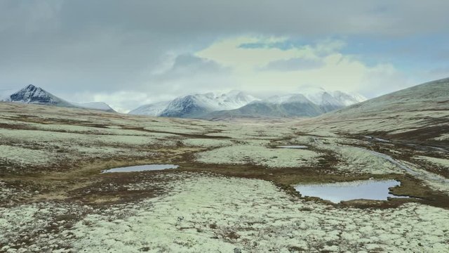 Snowy mountains and arctic tundra moss valley Rondane national park in Norway travelers couple hiking aerial drone view