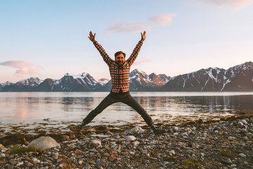 Happy man jumping outdoor travel active healthy lifestyle adventure vacations in Norway success concept happiness joyful positive emotions mountains and sea view