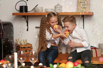 Boy and girl celebrate New Year, drink juice, eat fruit and make wishes in the New Year decorations