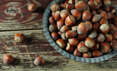 Top view of hazelnuts on a gray plate close-up on an old wooden table. 