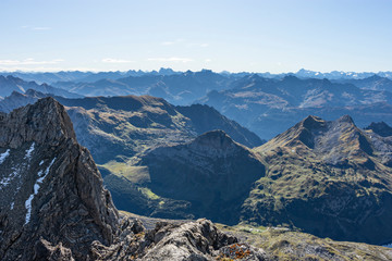 View from the summit of Rote Wand mountain (Vorarlberg, Austria). Wild alpine landscape with mountain ranges under blue sky.