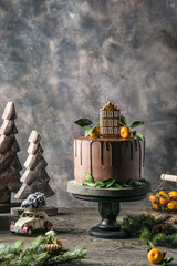 Naklejka na ściany i meble Chocolate cake with gingerbread on a dark background with mandarins and branches of Christmas tree