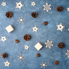 Obraz na płótnie Canvas Winter flat lay with cinnamon, anise, cones, wooden snowflakes on a blue textural background. Concept for Christmas and New Year.