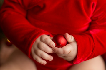 baby's hands. the child is holding a Christmas ball. Christmas toy